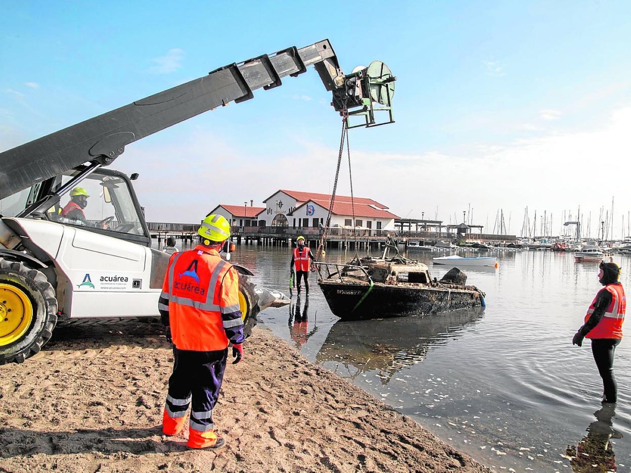 Operarios sacan con una grúa un barco hundido en la playa de La Concha de Los Alcázares, ayer. 