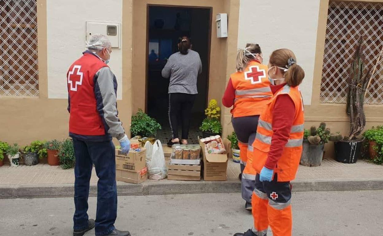 Tres voluntarios de la ONG reparten alimentos y otros productos básicos a familias necesitadas, en una imagen de archivo.