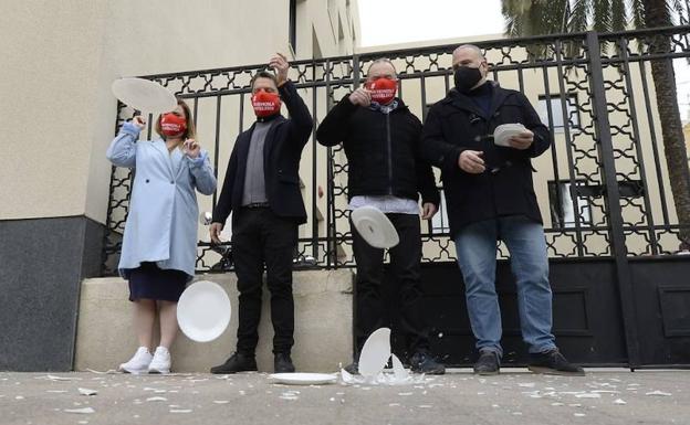 Representantes de la patronal hostelera de la Región rompen platos frente a la Delegación del Gobierno, en Murcia, como protesta ante la falta de ayudas, este martes.