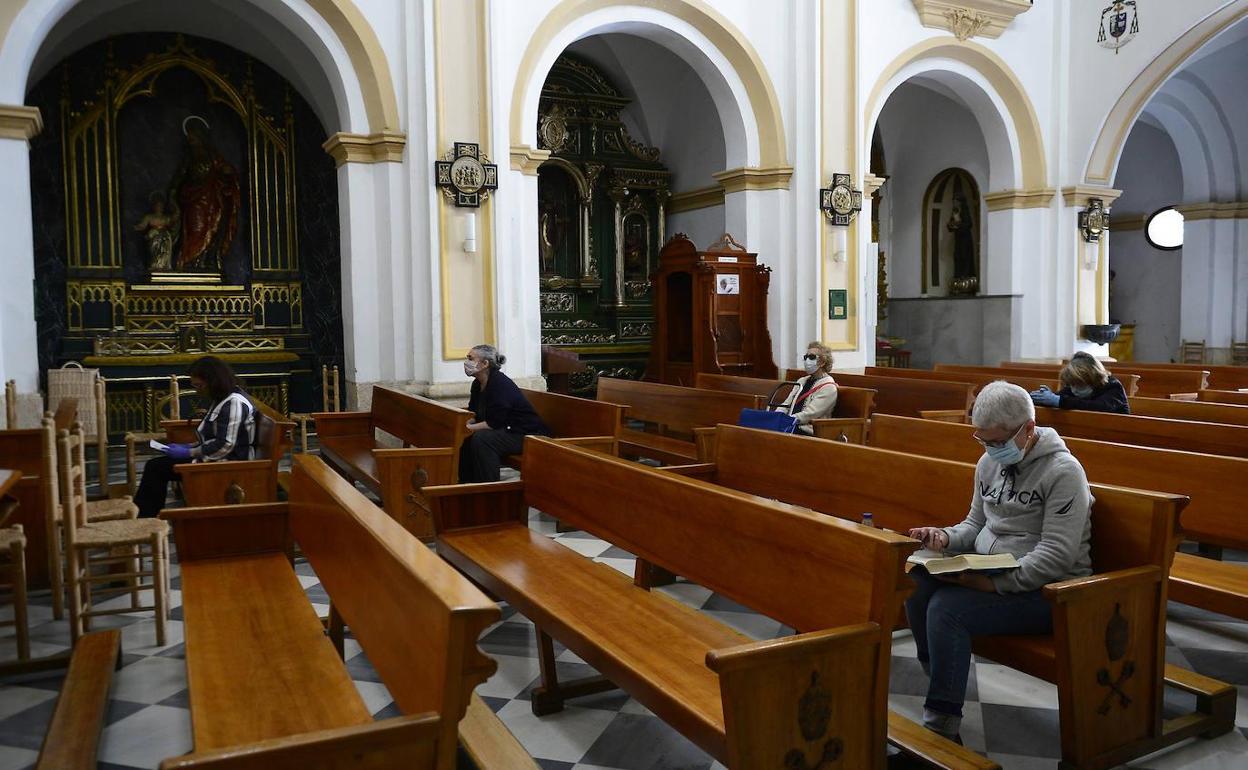 Fieles con mascarilla en una iglesia en una foto de archivo.