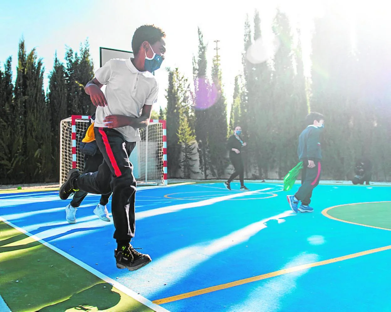 Un grupo de alumnos juega en una pista deportiva del centro. 