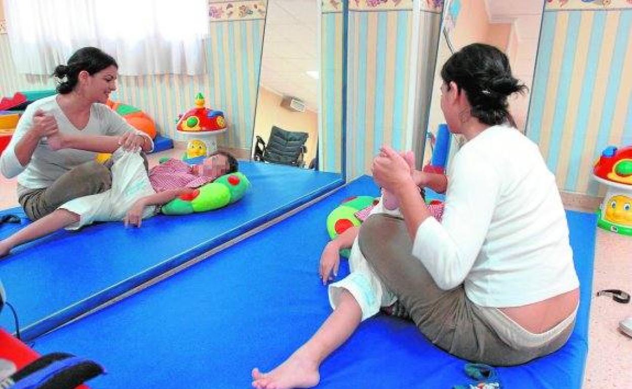 Una monitora atiende a un niño en un centro de atención temprana de Lorca. 