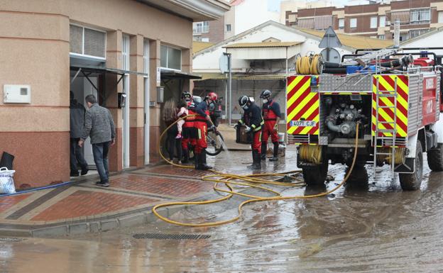 Los bomberos achican el agua de un garaje de la localidad, este domingo.