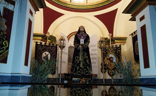 Nuestro Padre Jesús Nazareno, talla de vestir datada en el siglo XVIII, flanqueada por dos estandartes bordados de la cofradía.