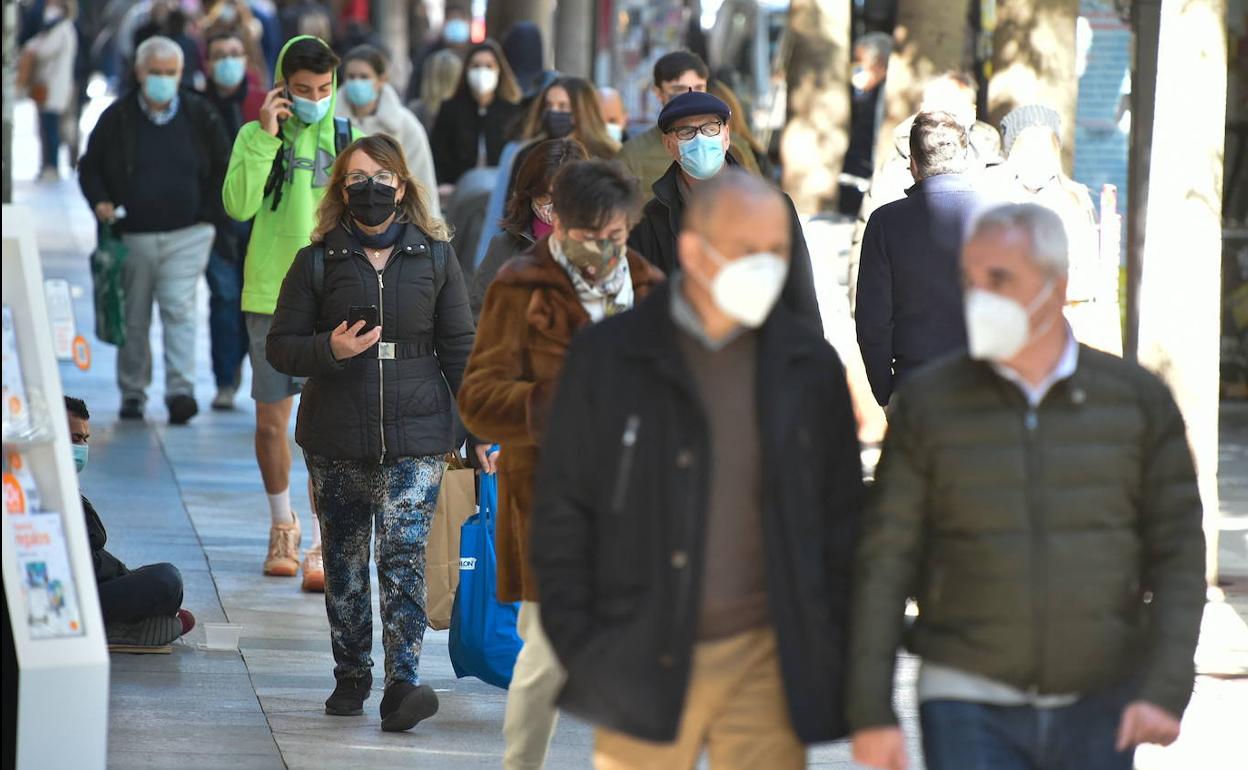 Viandantes pasean por una calle de Murcia con mascarilla. 