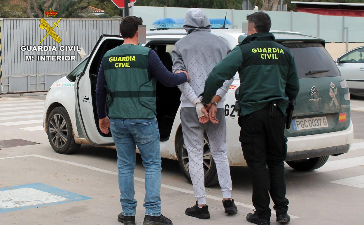 Dos guardias civiles trasladan al último detenido del grupo criminal.
