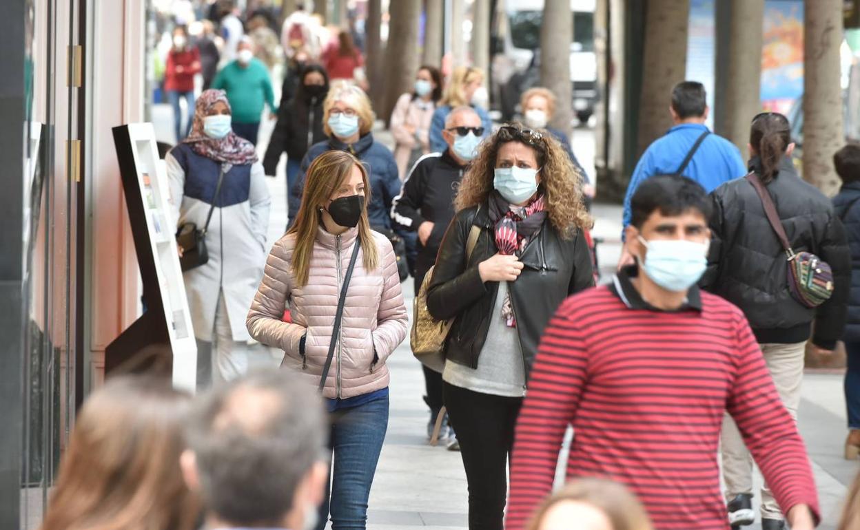 Varias personas caminan por el centro de Murcia con mascarillas.