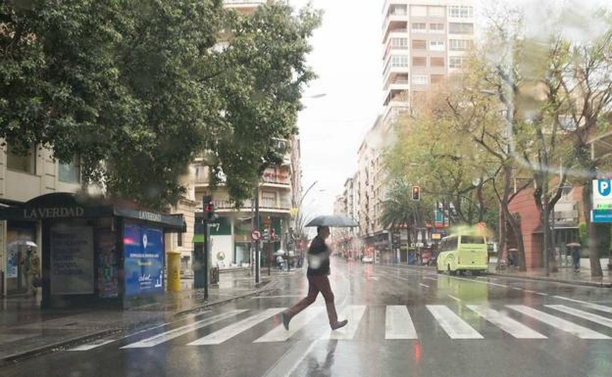 Un hombre cruza una calle de Murcia bajo la lluvia, en una imagen de archivo. 