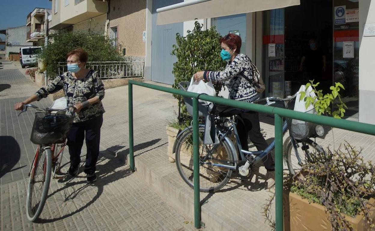 Fina y Carmen aseguran la compra en la cesta y en el asiento trasero de sus bicicletas de paseo, que han tenido que desempolvar para hacer la compra tras el incidente del puente. 