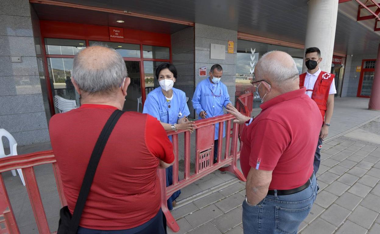 Vecinos de Murcia citados ayer para vacunarse piden explicaciones al personal sanitario y los voluntarios de Cruz Roja, en el estadio Enrique Roca. 