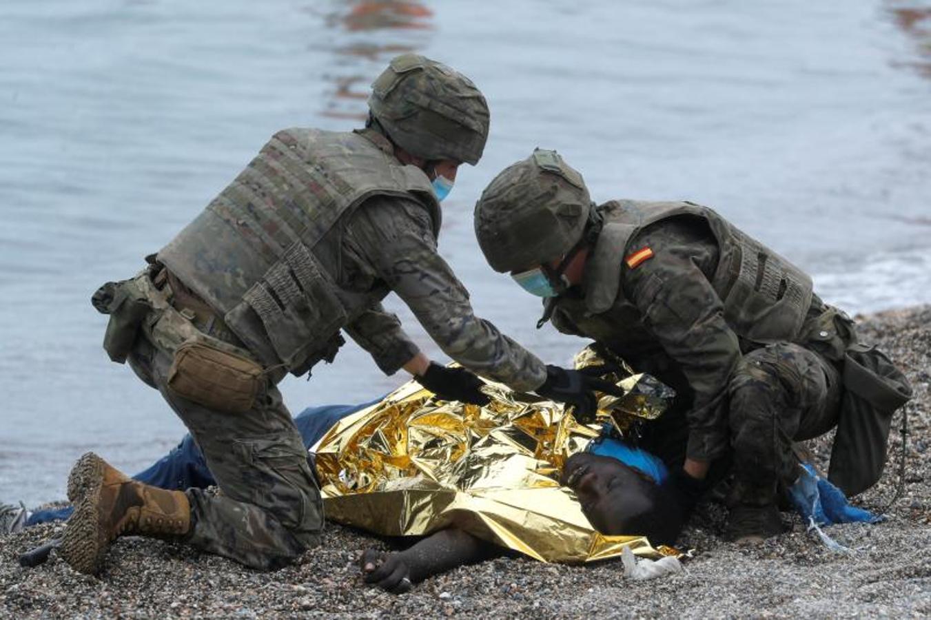 Dos militares atienden sobre la arena a una persona con síntomas de hipotermia.