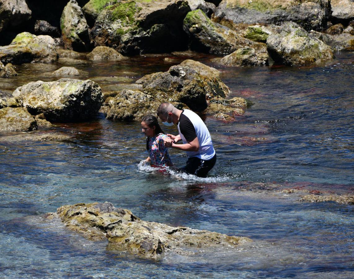 Una joven recibe ayuda para alcanzar la playa de la ciudad autónoma.