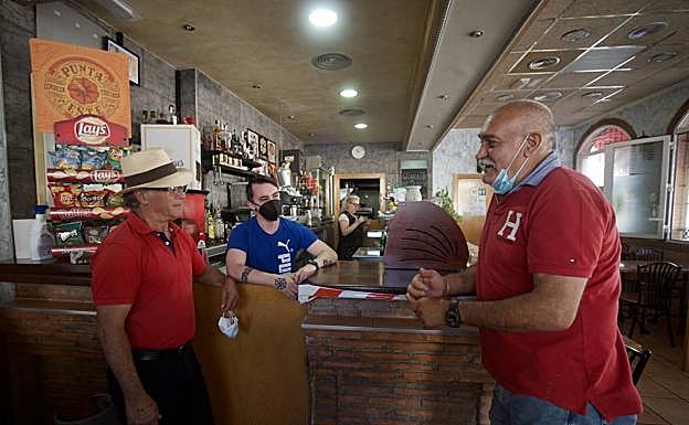 Dos clientes conversan con el hijo del propietario del bar Virgen de la Purísima, que tiene que cerrar. 