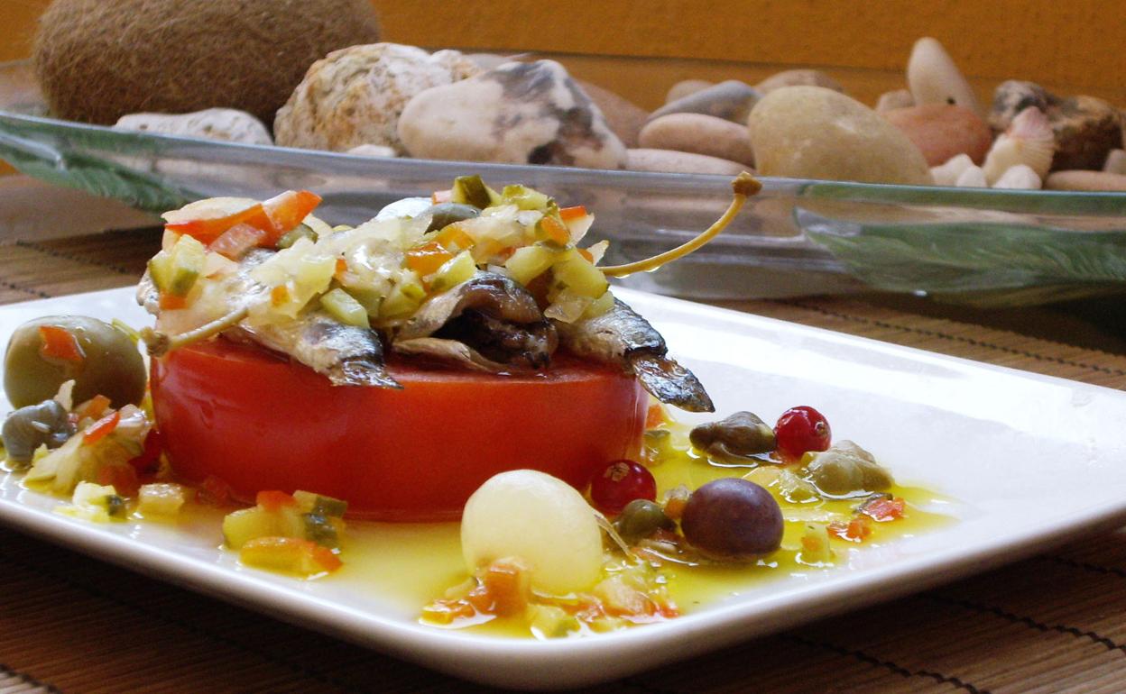 Lata de sardinas sobre tomate fresco