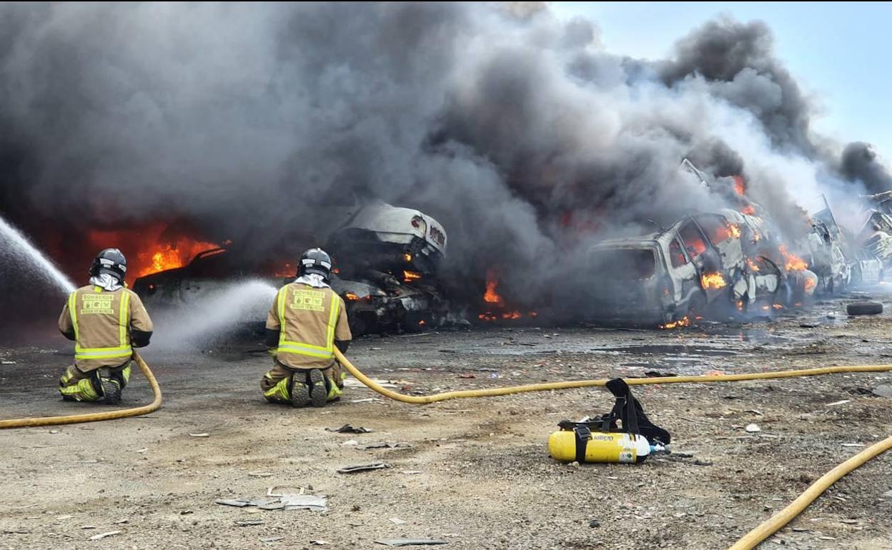 Dos bomberos trabajan para sofocar el incendio.