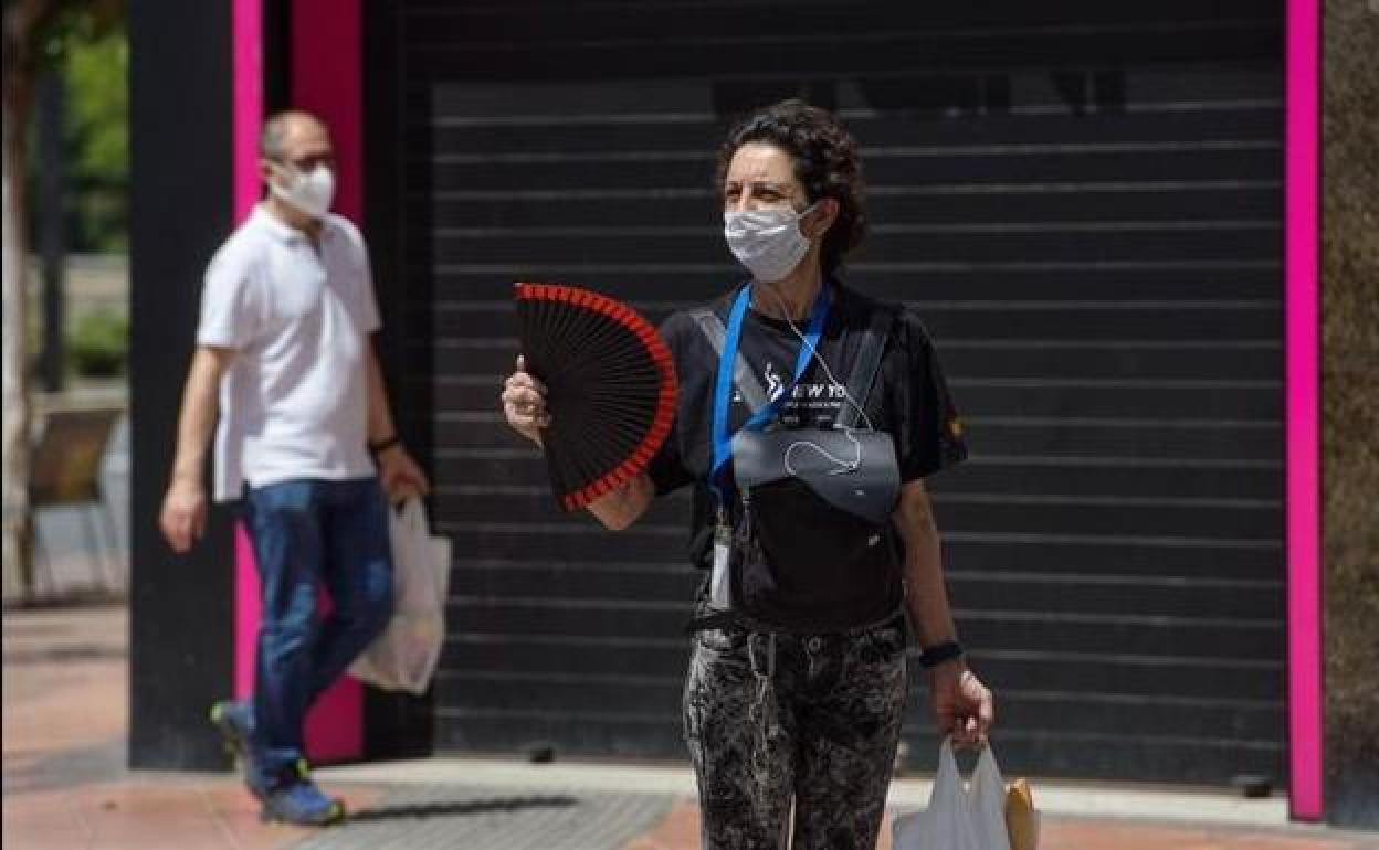 Una mujer con mascarilla se abanica en una calle de Murcia en una foto de archivo. 