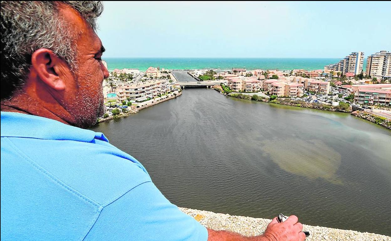 Un vecino observa desde lo alto el canal de Marchamalo, en La Manga del Mar Menor, en una imagen tomada el pasado domingo. 