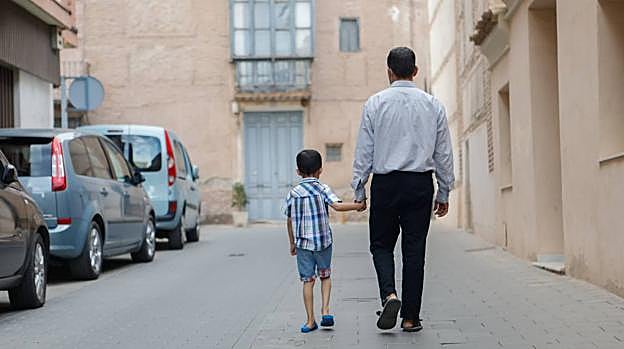 Farhad pasea tranquilamente por una calle mientras coge de la mano a su hijo, con el que fue rescatado de Afganistán. 