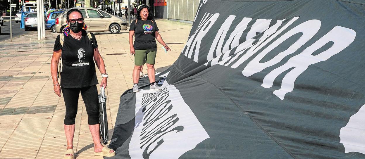 Dos activistas ante una de las pancartas desplegadas ayer en la puerta de la Asamblea Regional, en Cartagena. 