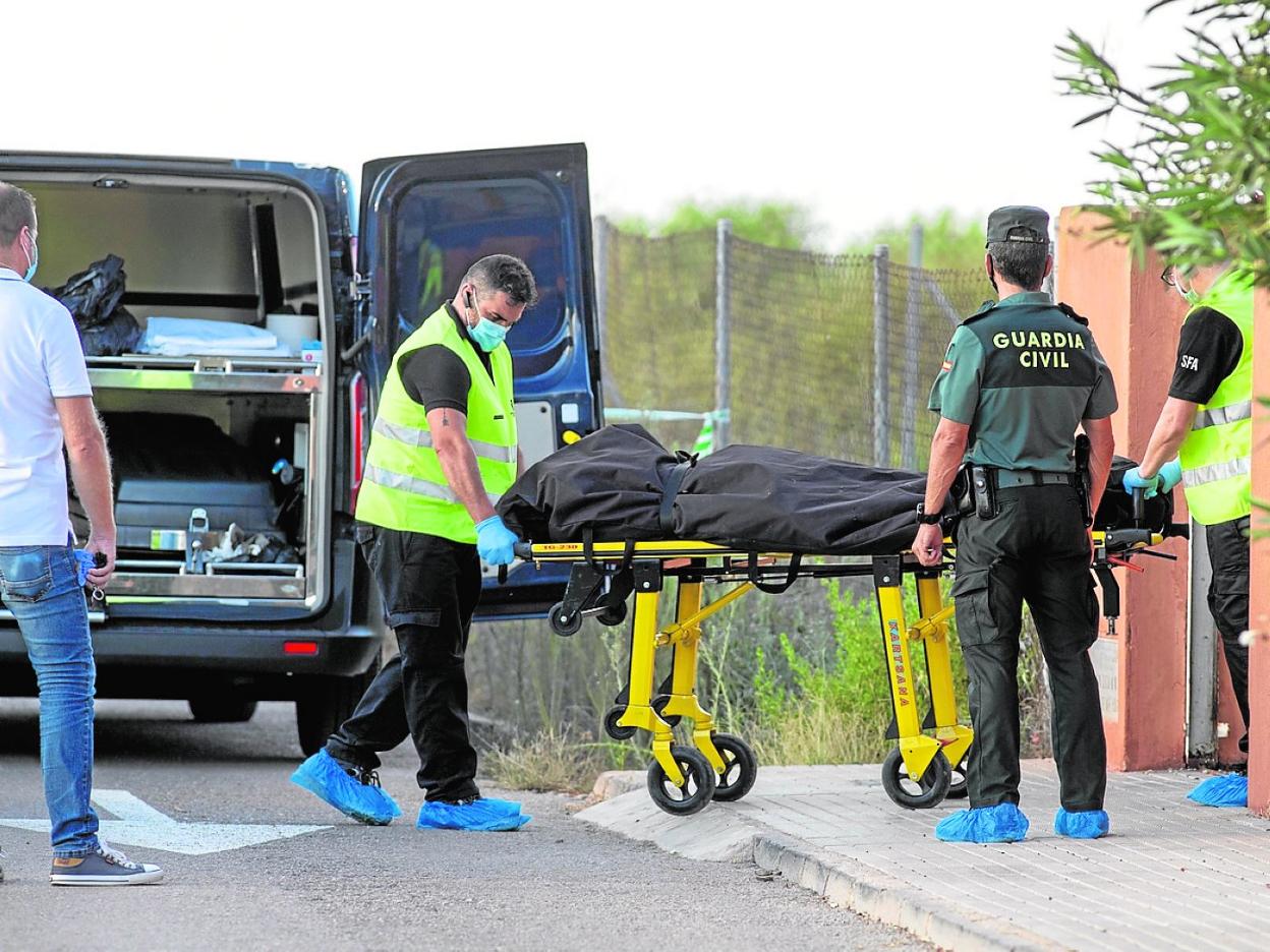 Agentes judiciales trasladan el cadáver desde el interior de la vivienda. 