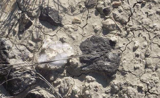 Detalle de una piedra ígnea negra a la derecha y evaporita blanca traslúcida a la izquierda, en las inmediaciones de los Cabecicos Negros de Fortuna.