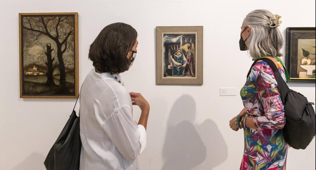 Dos visitantes contemplan uno de los cuadros expuestos.