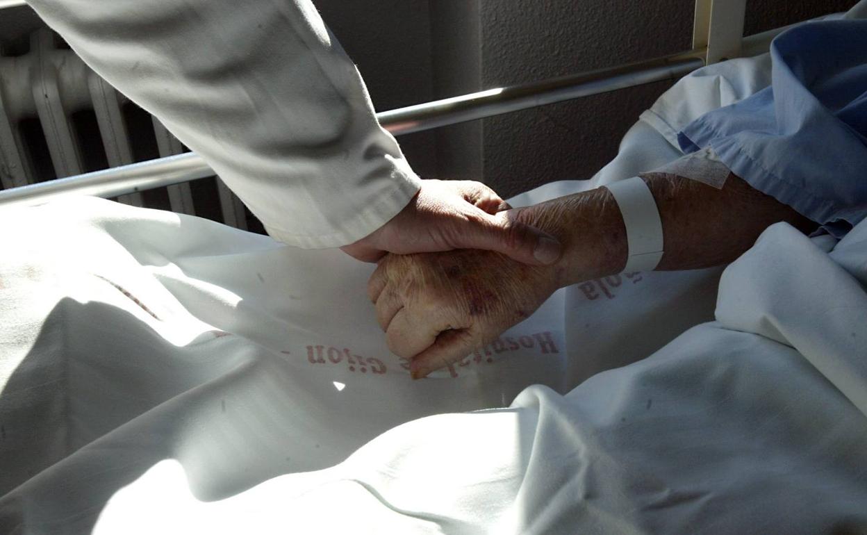 Un sanitario sostiene la mano de un paciente en una imagen de archivo.