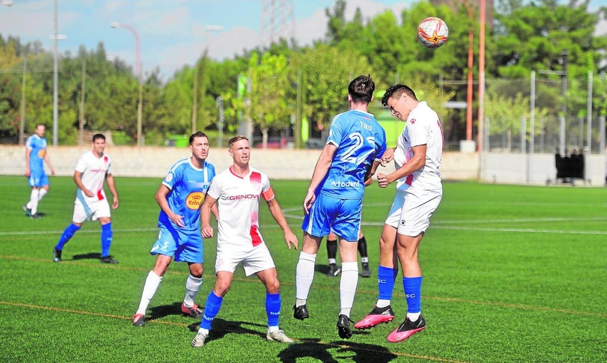 Tiku, del Caravaca, cabecea ante la atenta mirada de Higgins, capitán del Racing Murcia, ayer. 