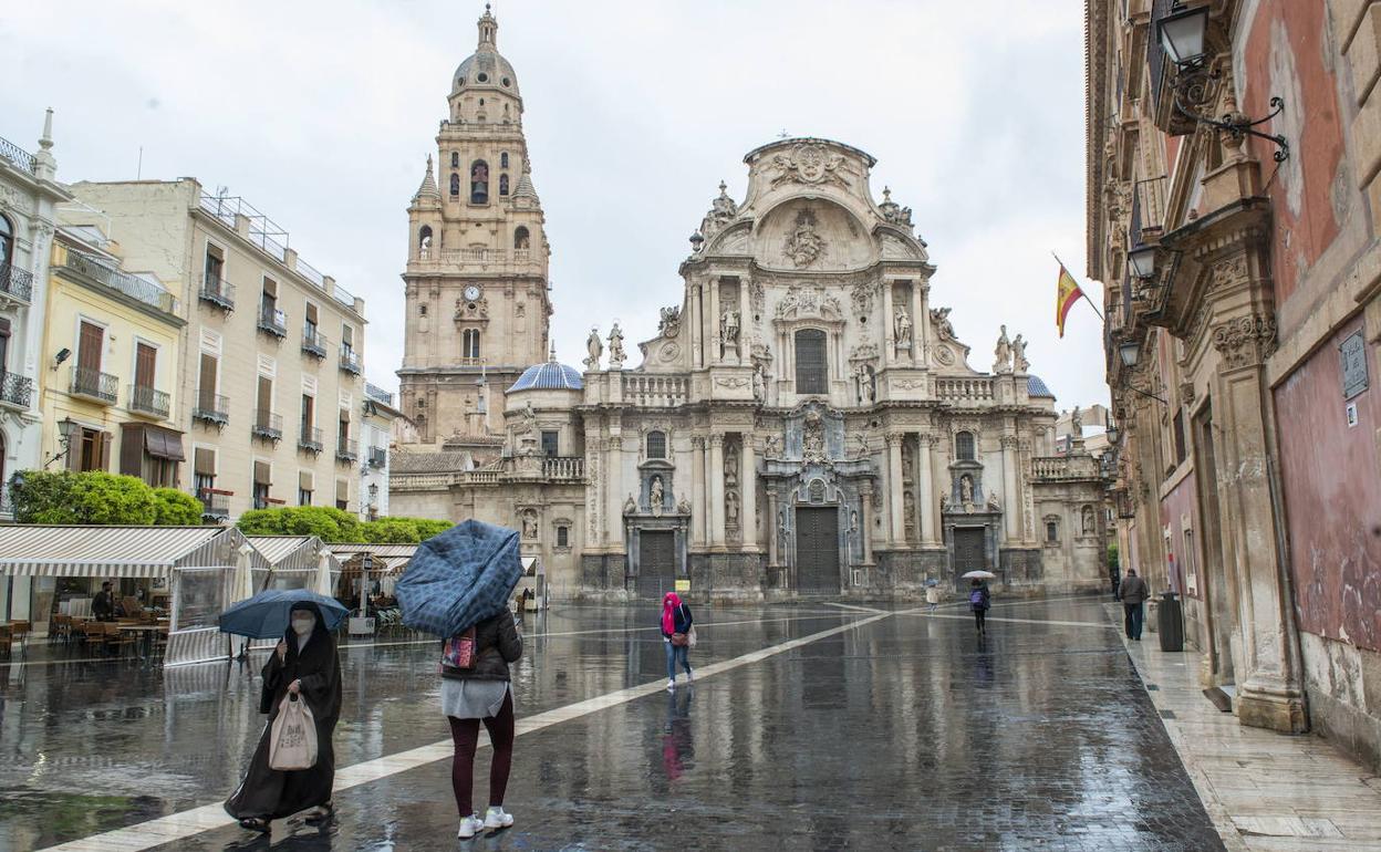 Viandantes con paraguas frente a la Catedral de Murcia, en una foto de archivo.