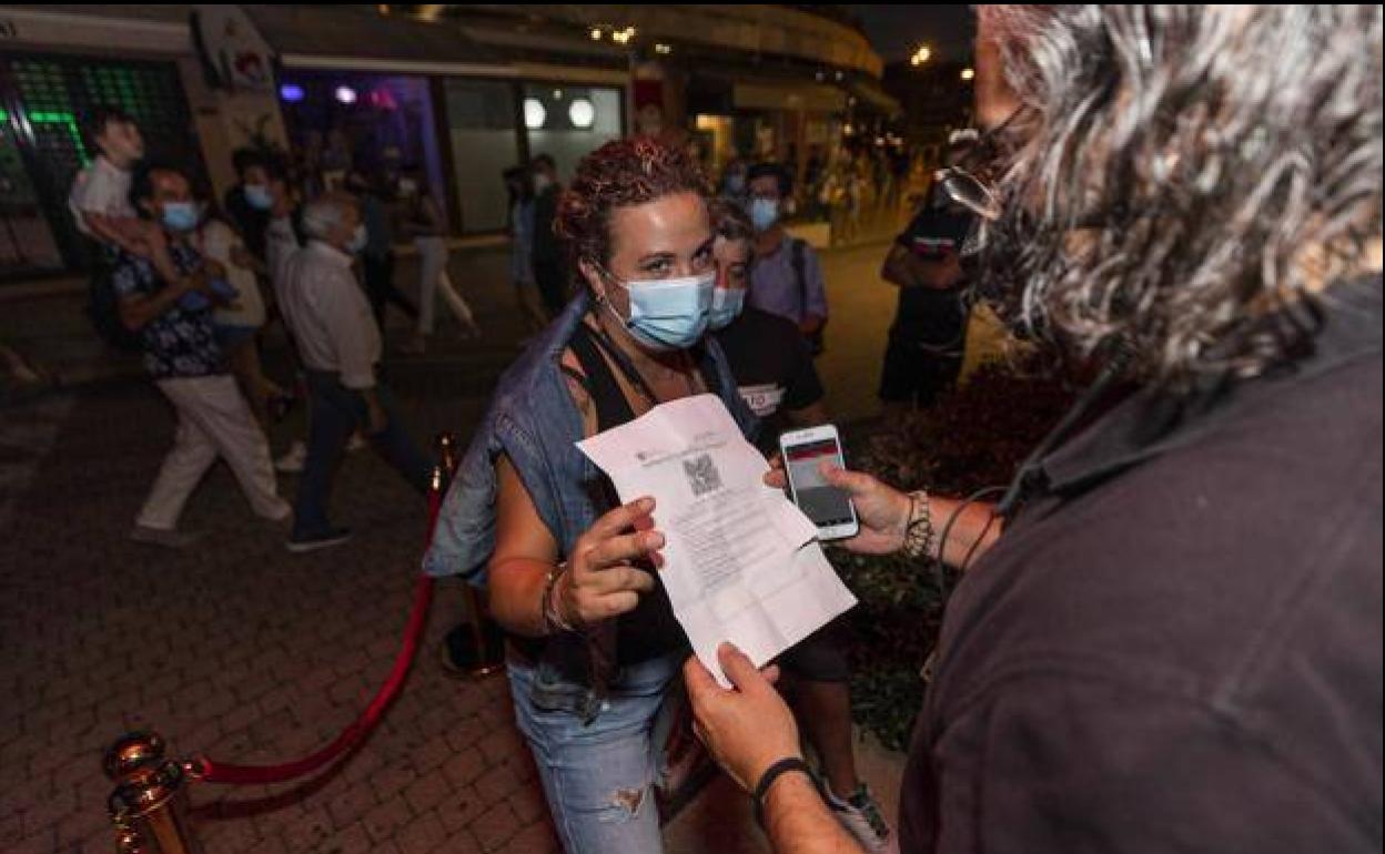 Un trabajador pide el certificado Covid a una cliente en la puerta de un local.