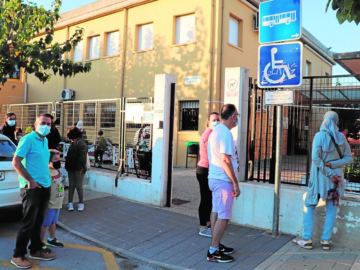 Varias personas en la zona de estacionamiento en la entrada al colegio El Sifón, en Molina. 