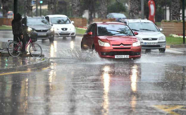 Varios coches circualando con mucha agua en la calzada, en una imagen de archivo.