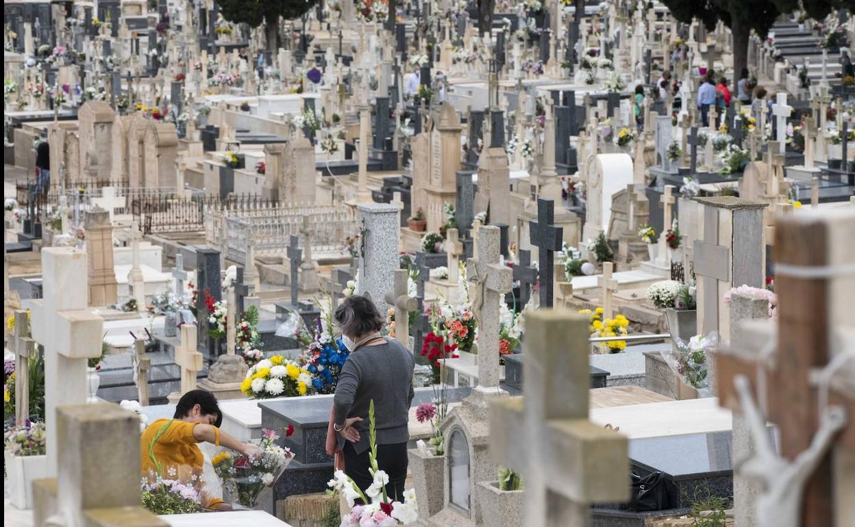 Dos mujeres arreglan las flores de una tumba del cementerio de Nuestra Señora de los Remedios de Cartagena, este lunes. 