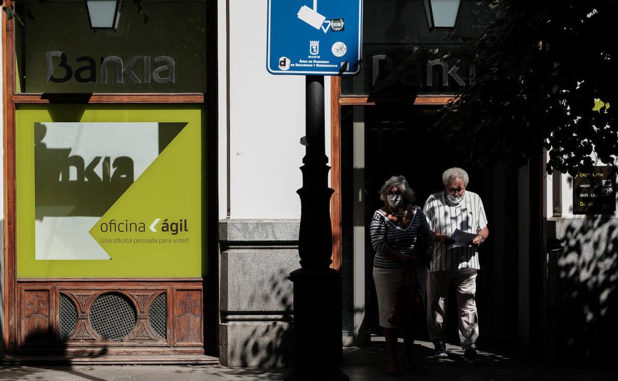 Dos personas caminan junto a una sucursal bancaria en Madrid. 