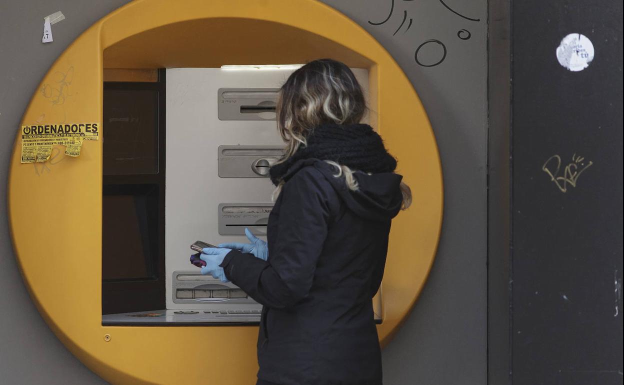 Una mujer saca dinero en un cajero, en una imagen de archivo.