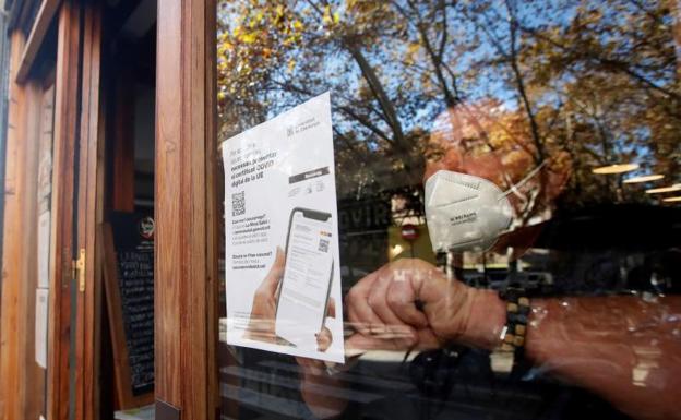 Un camarero coloca el cartel que avisa de control de vacunación en un restaurante de Barcelona. 