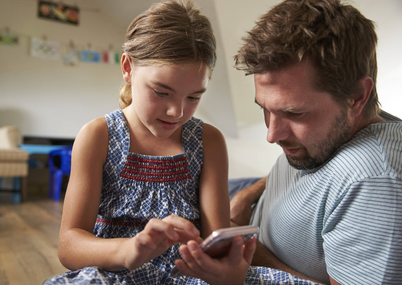 Un padre y su hija utilizando un teléfono móvil.