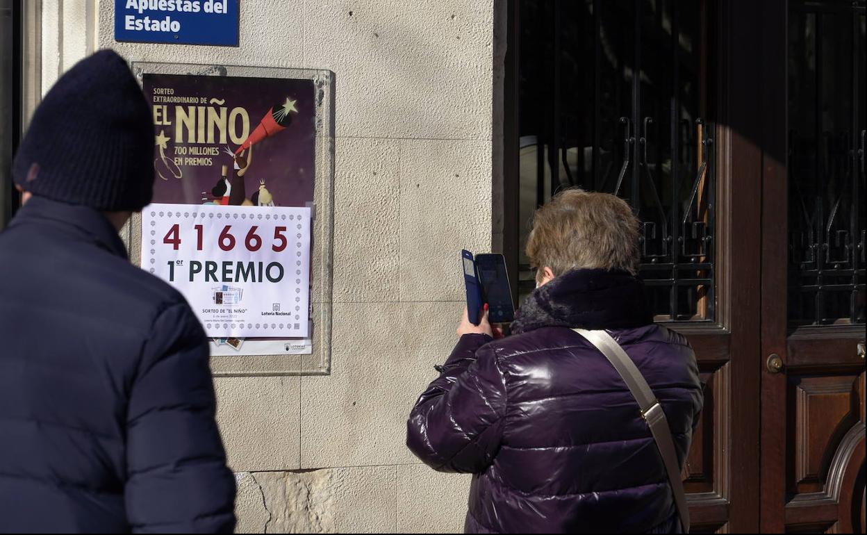 Una mujer hace una foto al número correspondiente al 'Gordo' de la Lotería del Niño en la administración Carmen situada en la calle Muro del Carmen.