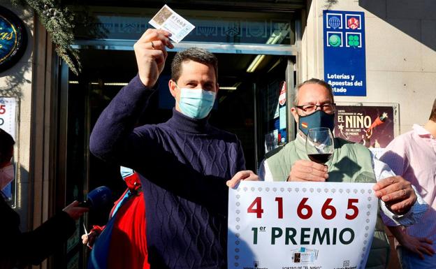 Uno de los agraciados muestra este jueves el décimo ganador del primer premio del sorteo extraordinario de la Lotería del Niño junto a los trabajadores de la Administración de Lotería número 6 de Logroño.