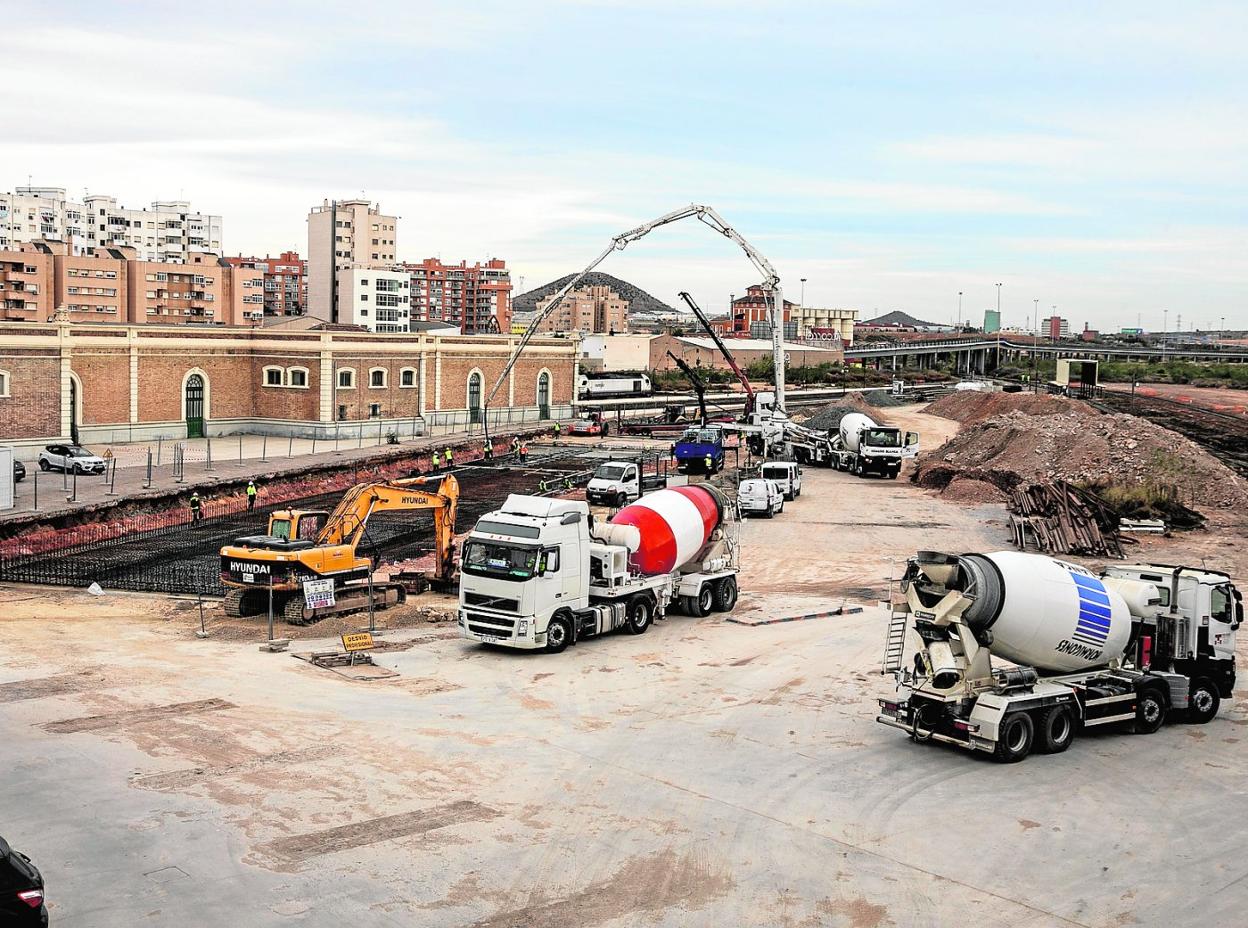 Obreros, grúas y camiones, en las obras junto a la estación. 