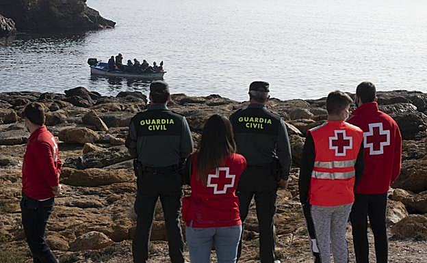 Agentes de la Guardia Civil y efectivos de Cruz Roja vigilan a las personas que han llegado este lunes a Isla Plana en patera.