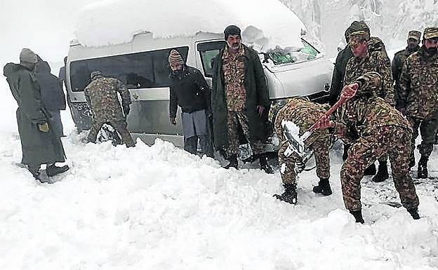 Miembros del Ejército paquistaní tratan de liberar uno de los vehículos atrapados por la nieve.