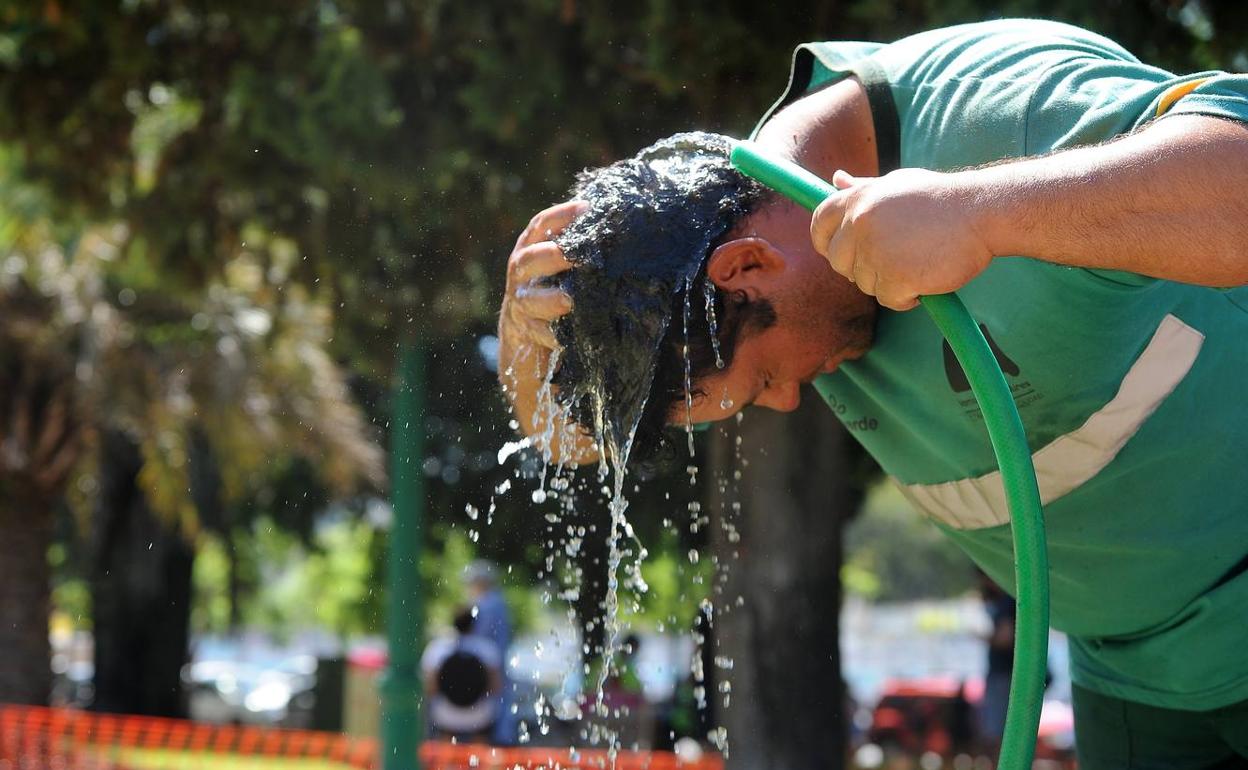  Un hombre se refresca con una manguera para mitigar la ola de calor que afecta estos días en Buenos Aires (