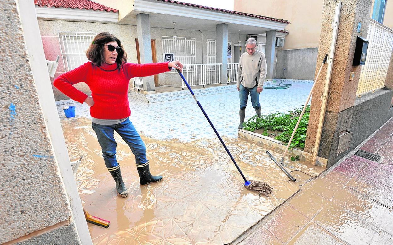 Vecinos de Los Alcázares afectados por inundaciones limpian la entrada a su vivienda en 2020. 