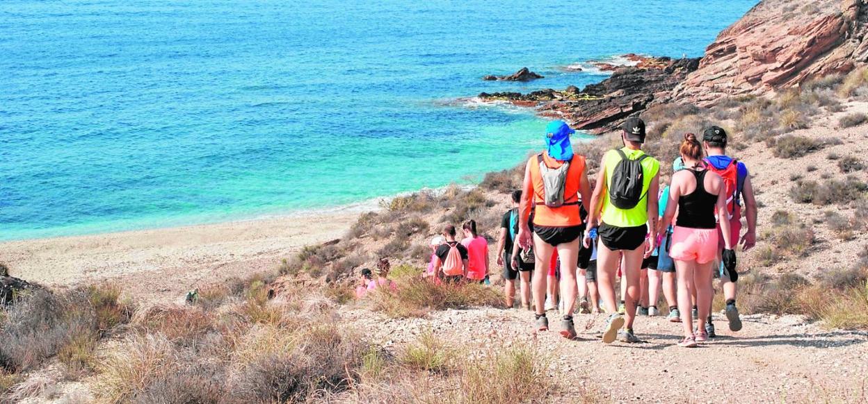 Senderistas recorriendo la costa lorquina en Calnegre. A la izquierda,presentación de la Semana Santa de Lorca en Fitur a cargo del vicealcaldey concejal de Turismo, Francisco Morales. 