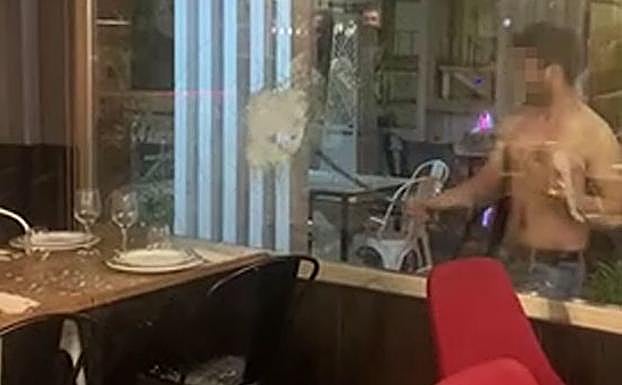 El hombre destroza el cristal del restaurante. 