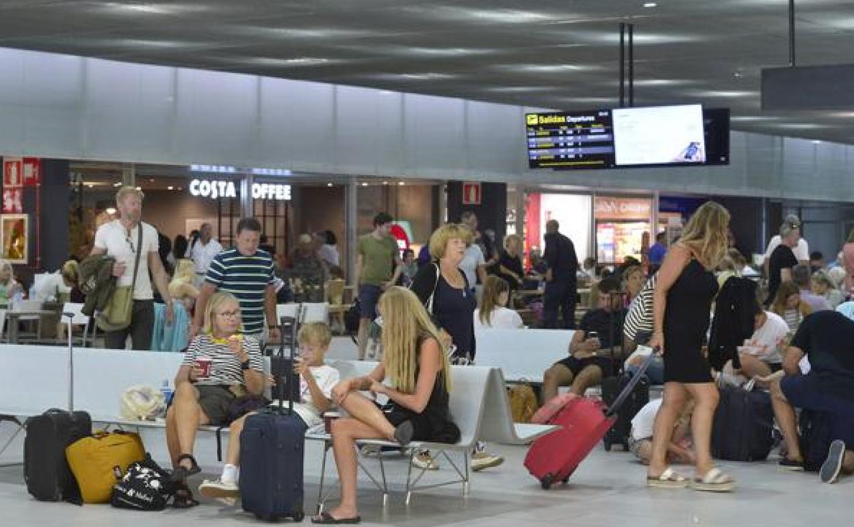 Pasajeros esperan en el área comercial del aeropuerto de la Región de Murcia, en una imagen de archivo. 