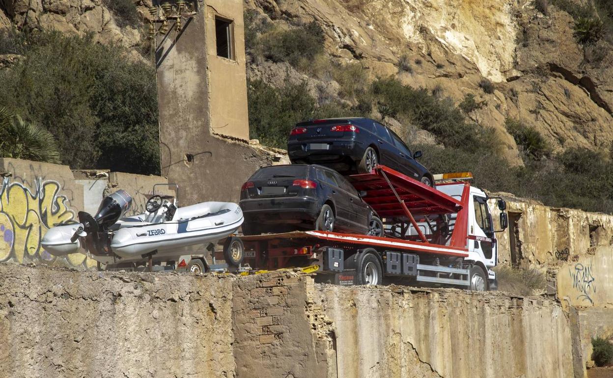 Una grúa traslada dos vehículos y una lancha neumática incautados a la red de narcotráfico.