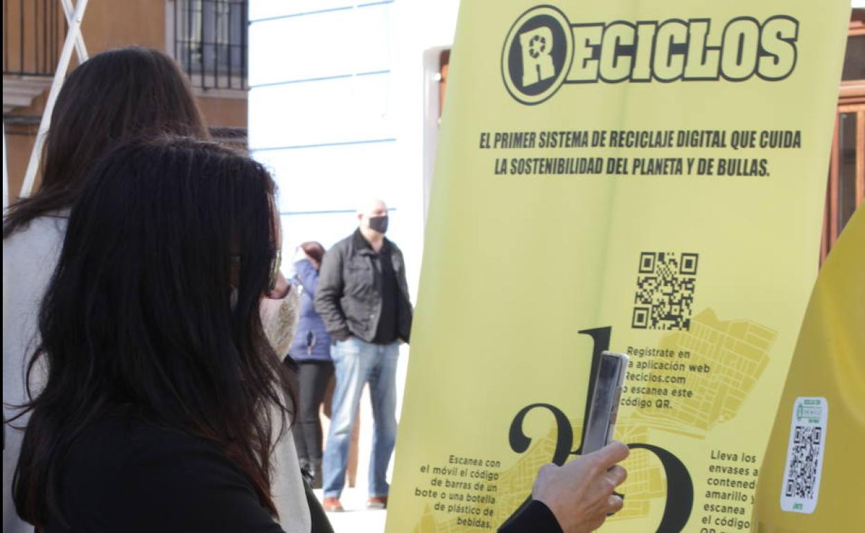 Una chica escanea el código QR de un contenedor de Reciclos, en Bullas (Murcia).