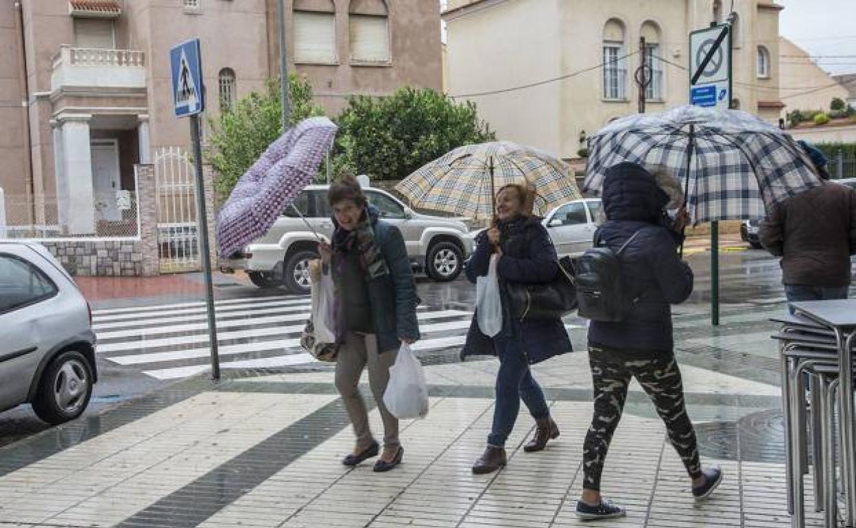 Mujeres se protegen del viento y la lluvia con sus paraguas, en una imagen de archivo.